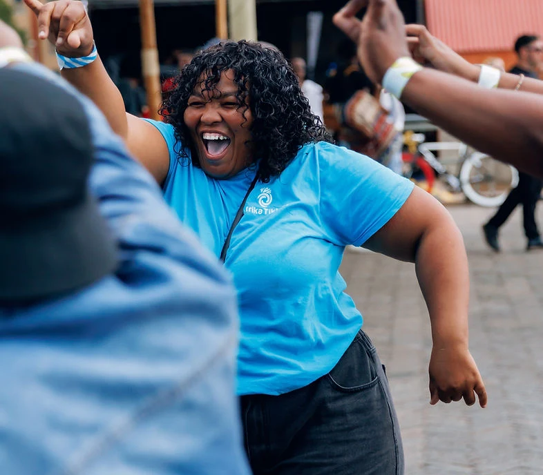 A woman in a blue t-shirt laughing and dancing in the crowd