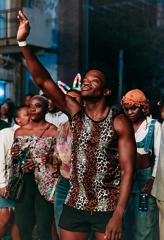 A man in a leopard vest raising an arm